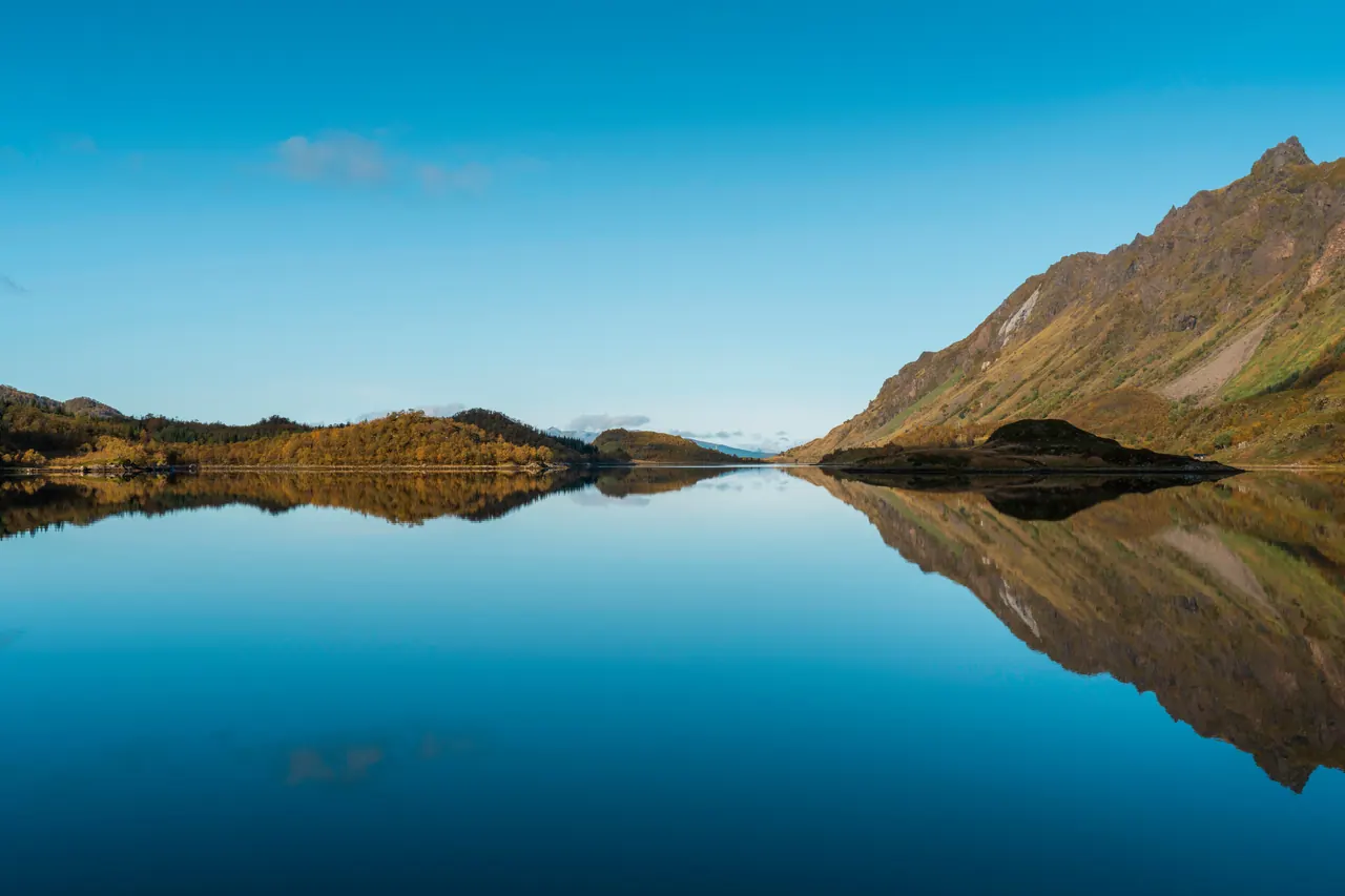 Tranquil reflection of mountains and blue sky in Lofoten Islands, Norway. Perfect autumn day.