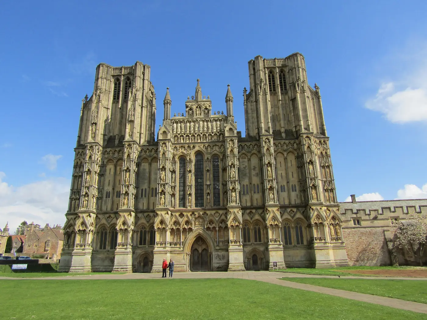 The west front of Wells Cathedral, its carved medieval facade of tiered statues rising above the green