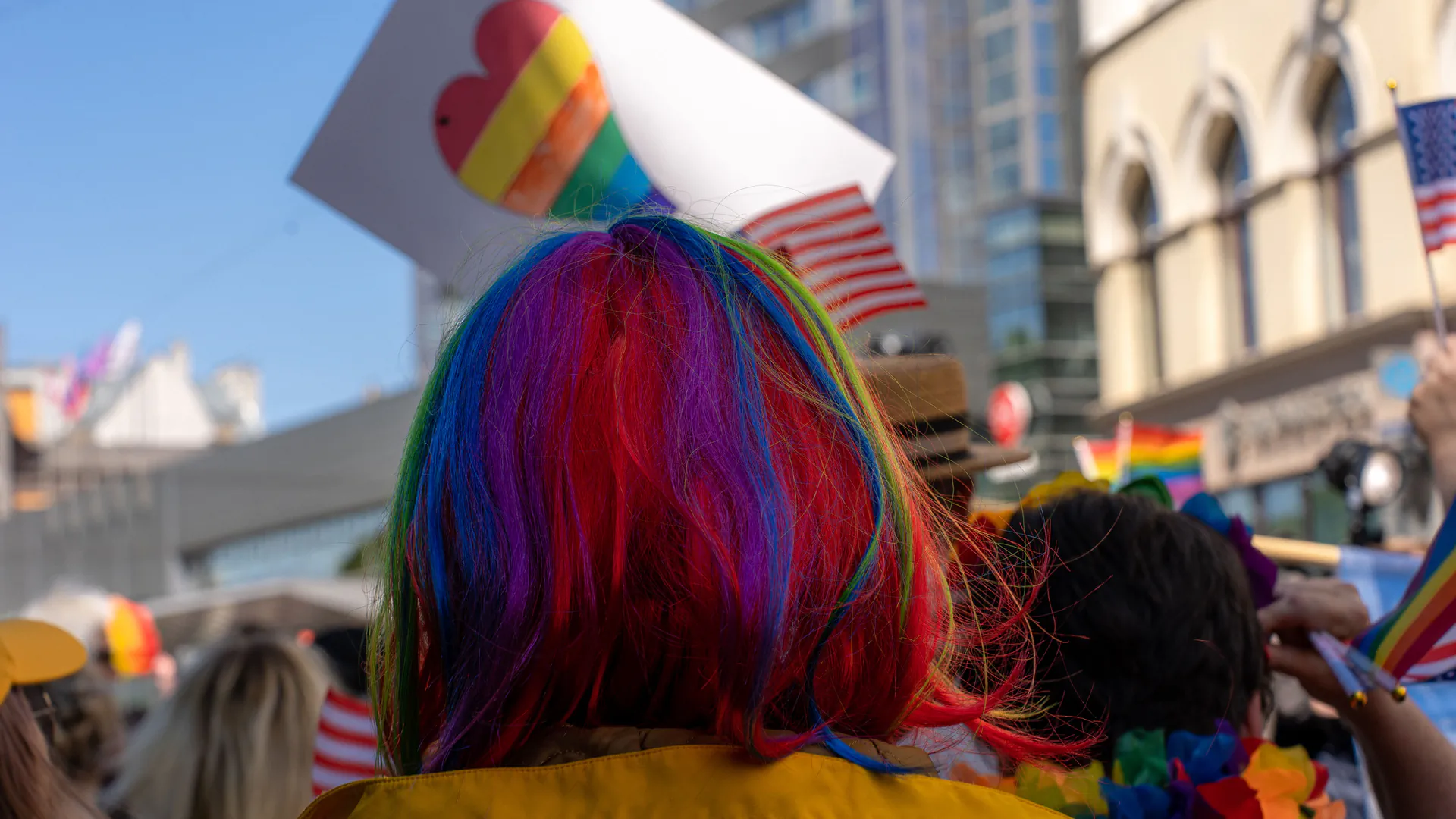 A dense, colorful Pride parade crowd on a city street