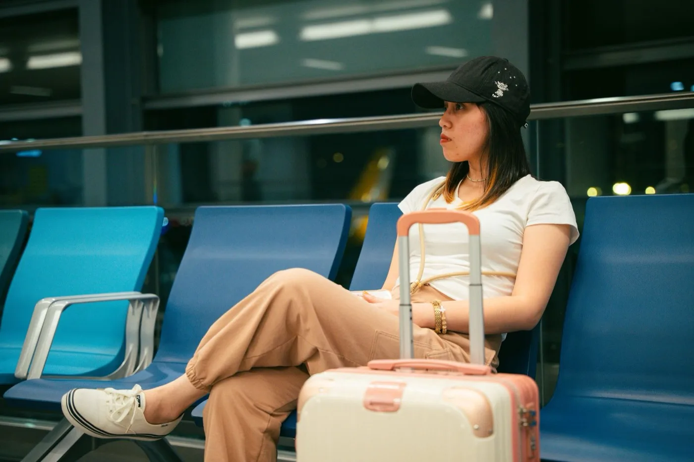 A traveller waiting with luggage in an airport terminal, checking a phone