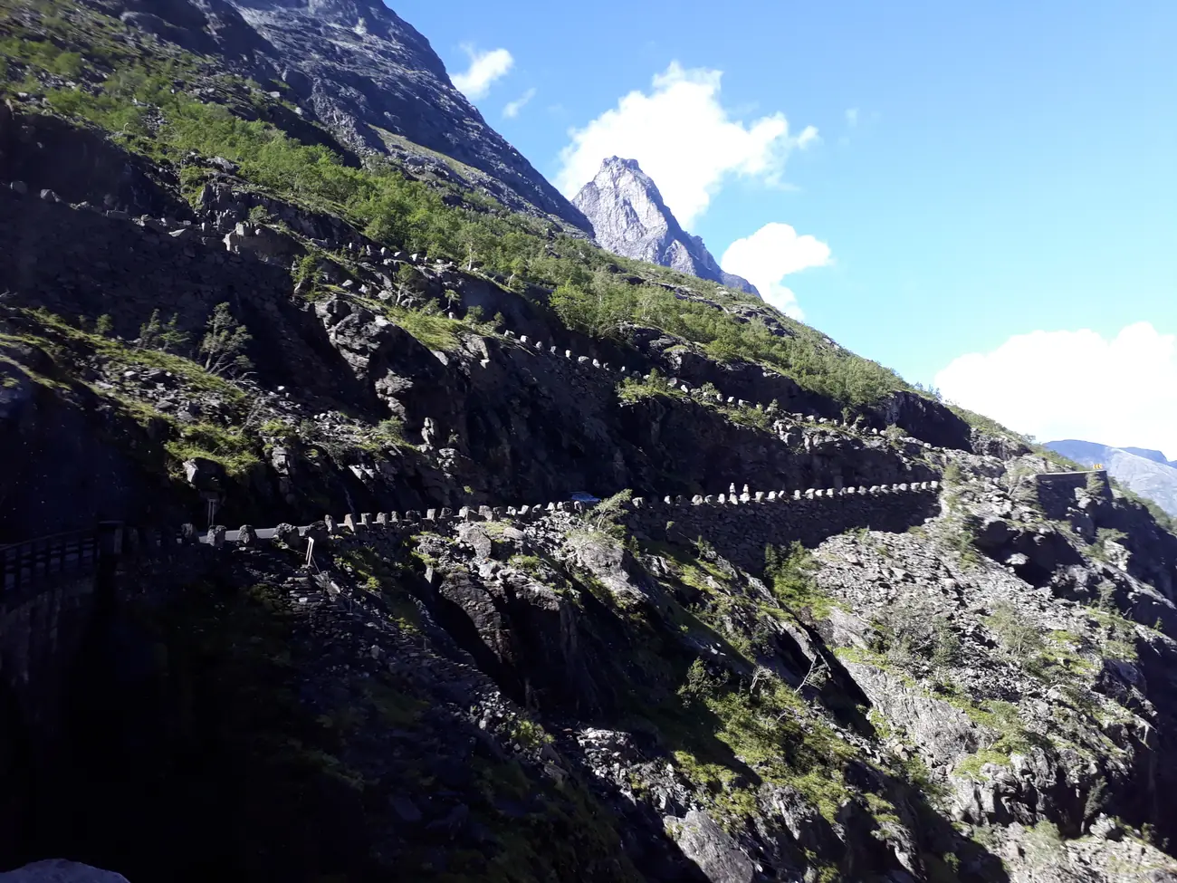 The Trollstigen mountain road in Norway, its hairpin bends stacked up a steep green mountainside