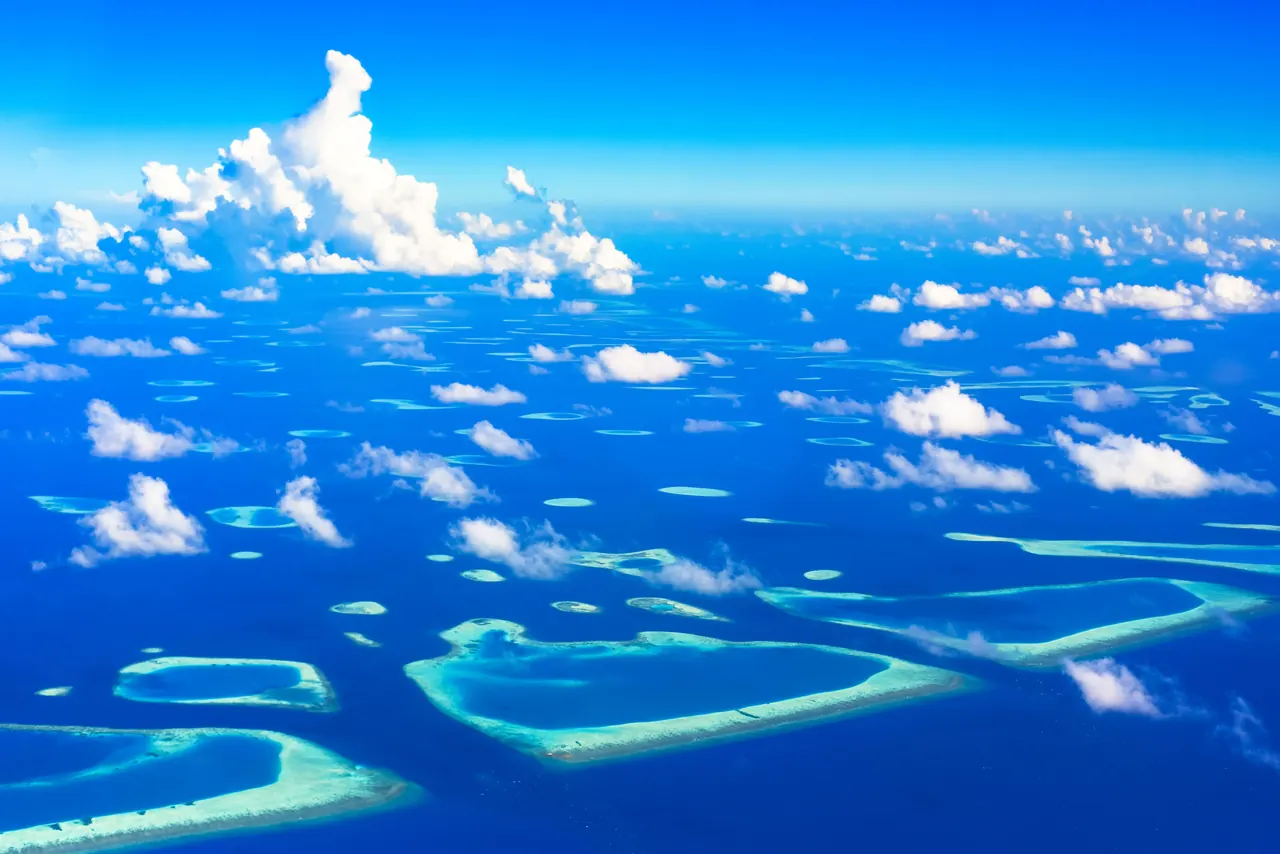 Stunning aerial view of a tropical archipelago with turquoise waters and scattered clouds.