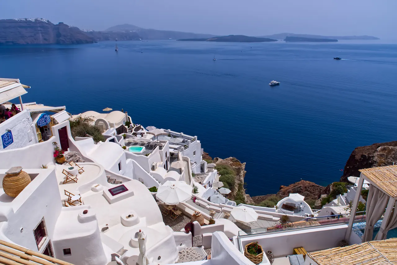 Iconic Santorini architecture with white buildings by the Aegean Sea under a clear blue sky.