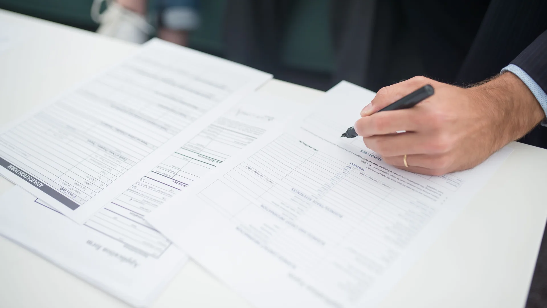A hand signing an insurance policy document at a desk