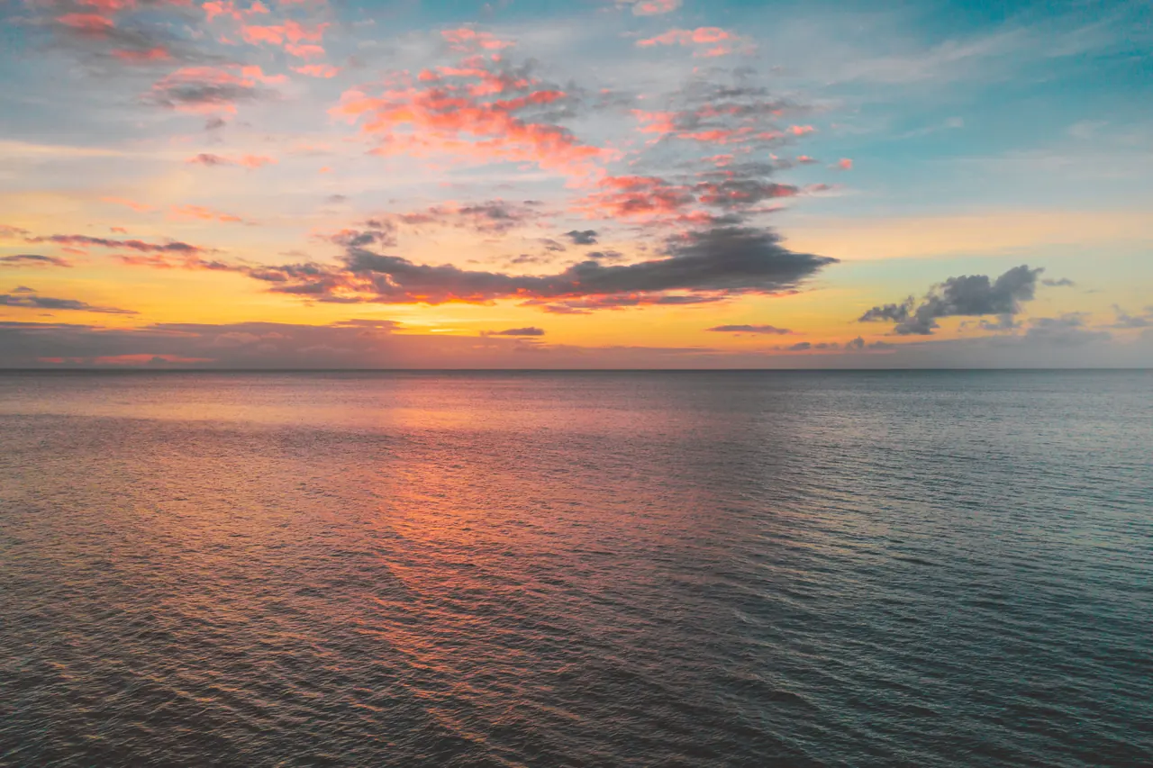 Breathtaking ocean sunset with colorful cloud reflections in calm waters, capturing nature’s beauty.