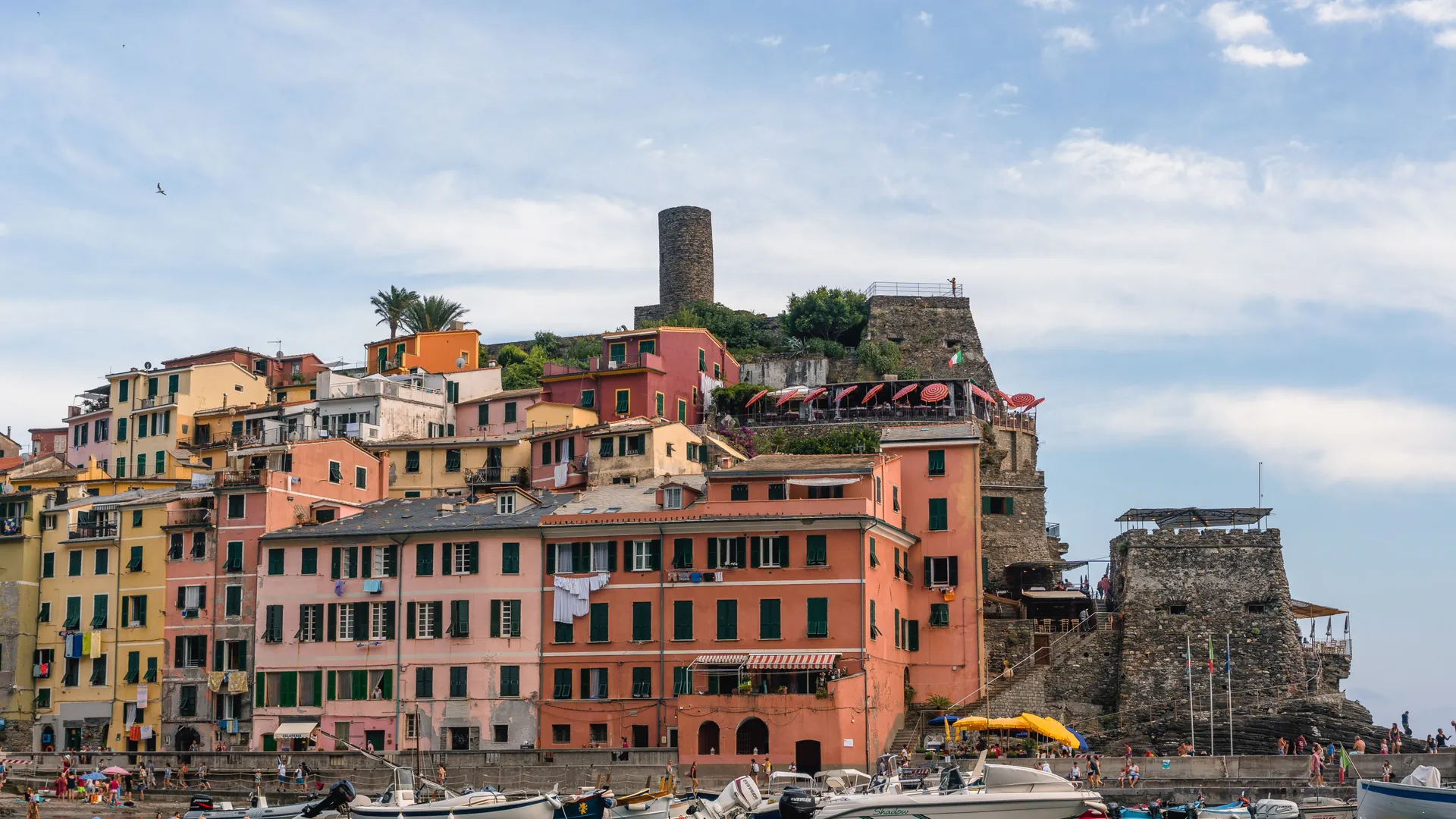 A Ligurian coastal town of tall pastel houses above a small harbor with moored boats
