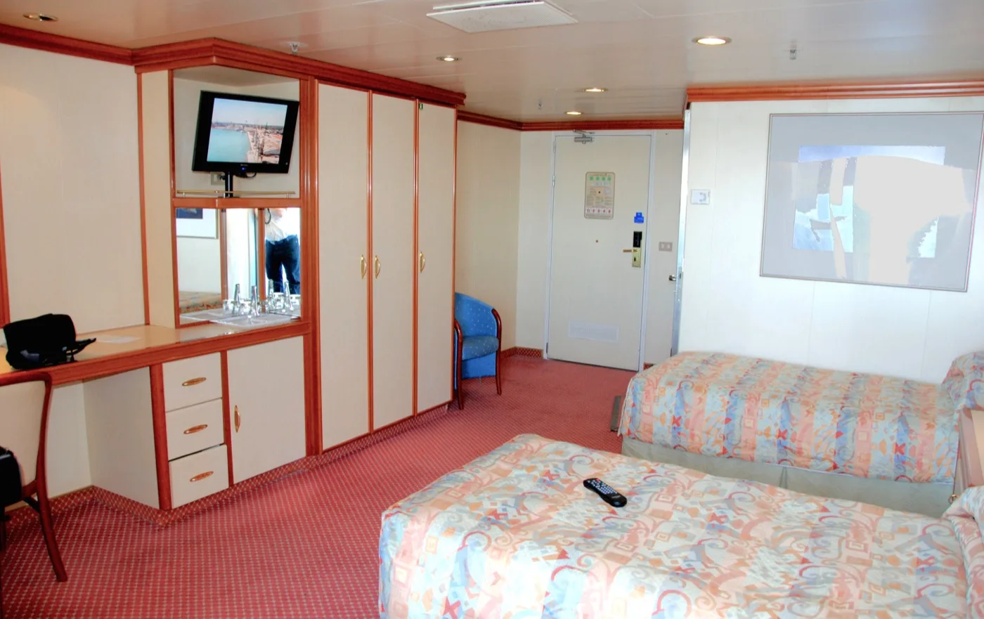 An accessible stateroom aboard Grand Princess, showing the widened clear floor space between the beds and the wardrobes