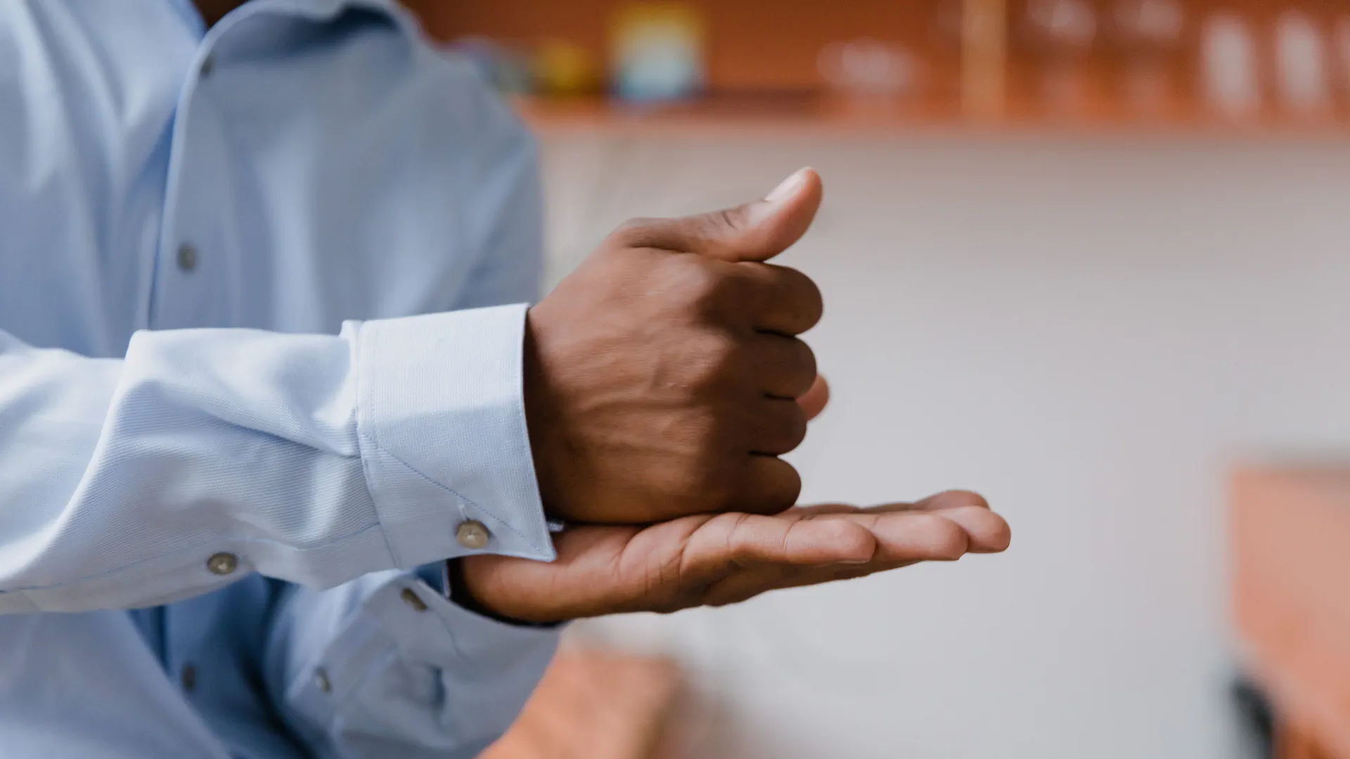 Close focus on a person's hands forming a sign, mid-conversation