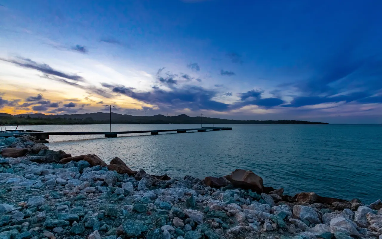 Dramatic evening sky over a rocky shoreline and pier in Puerto Plata, Dominican Republic.