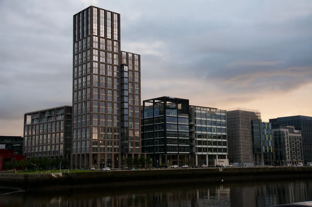 Modern buildings along Dublin's waterfront at twilight, their glass fronts reflected in the water