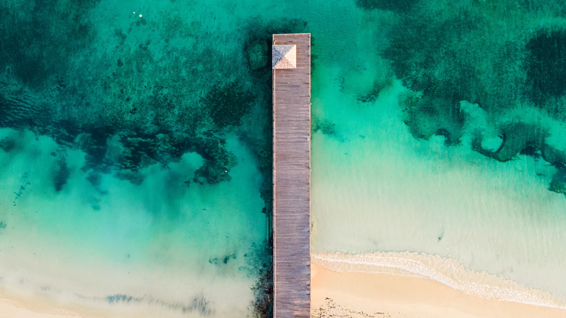 Aerial view of a wooden pier reaching into turquoise water off Jamaica’s north coast