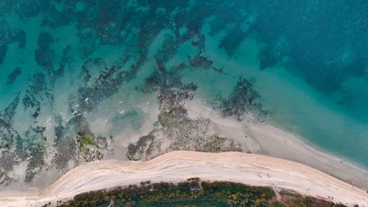 Aerial view showcasing the pristine shoreline with turquoise waters and sandy beaches.