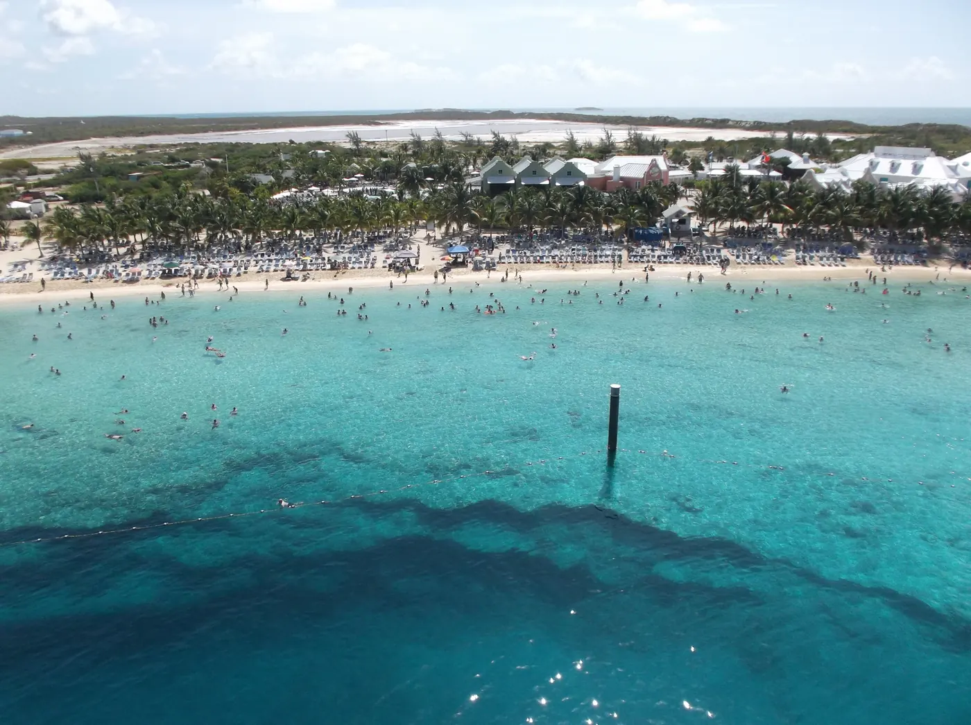 The Grand Turk Cruise Center seen from a ship berthed alongside, low terminal buildings and palms behind a curve of beach