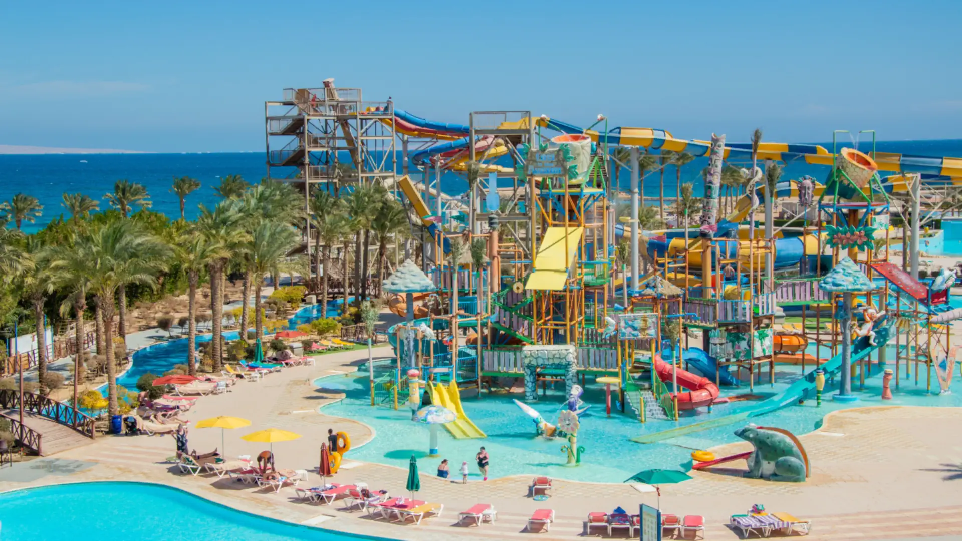 Bright water slides curving above a turquoise pool at a sunny water park