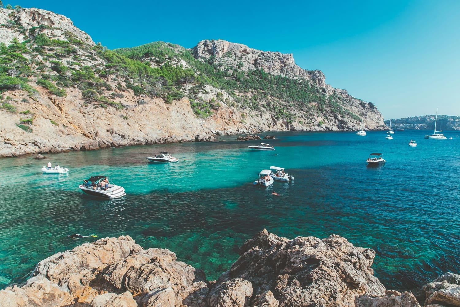Turquoise water, small boats and surrounding cliffs along the Mallorca coastline