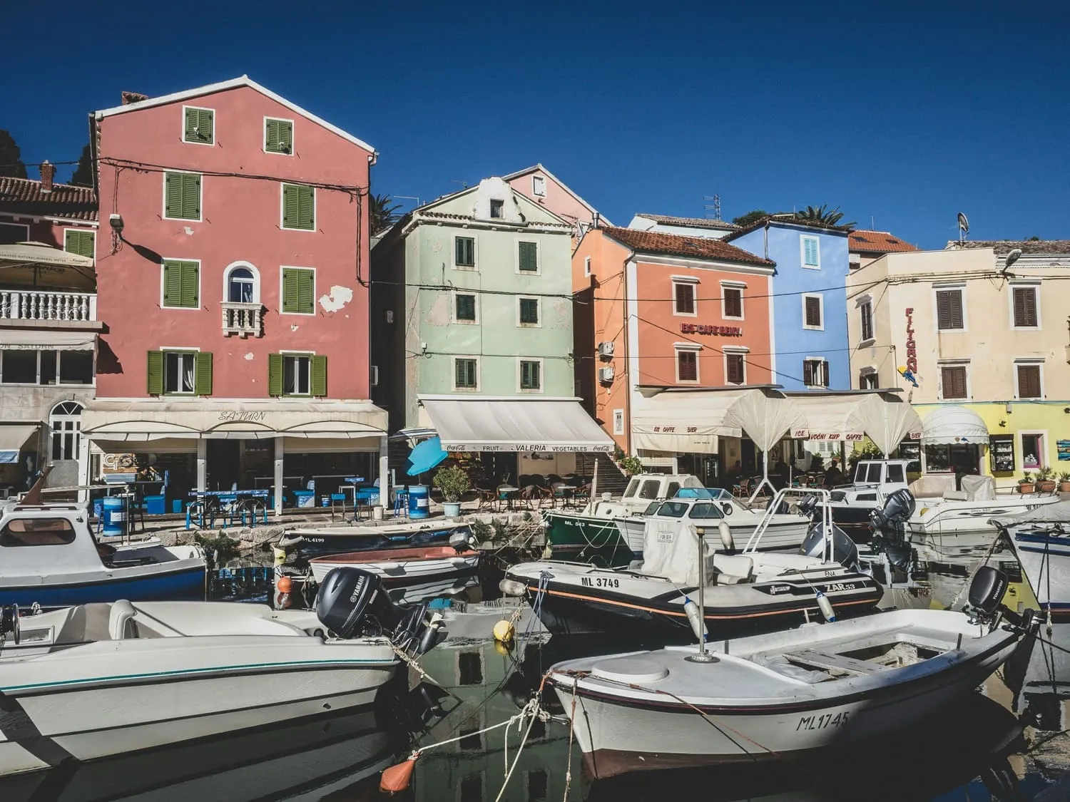 The colour-washed harbour of Veli Lošinj, Croatia — pastel buildings, docked boats and waterfront restaurants