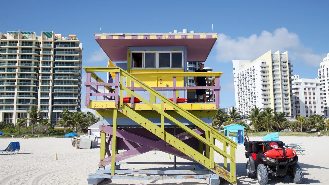 A lifeguard tower on Miami Beach in daylight, with the South Beach hotel line behind it