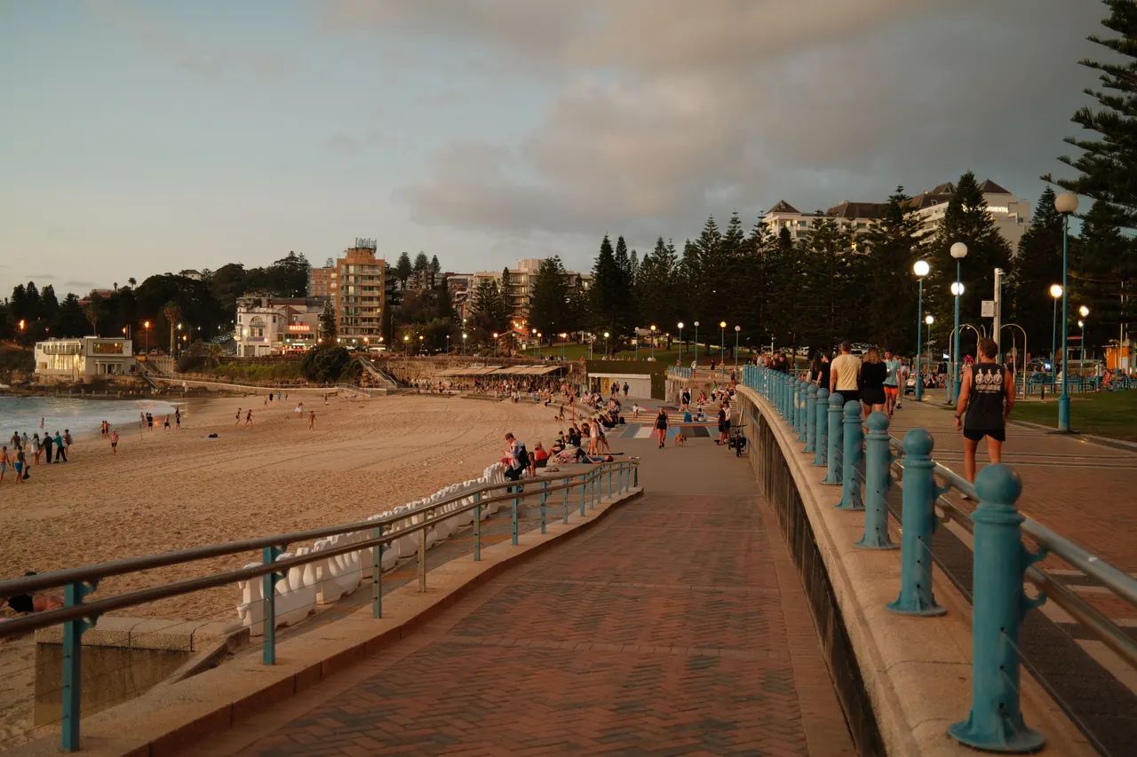 People enjoy a sunset stroll along Coogee Beach promenade in Sydney, Australia.