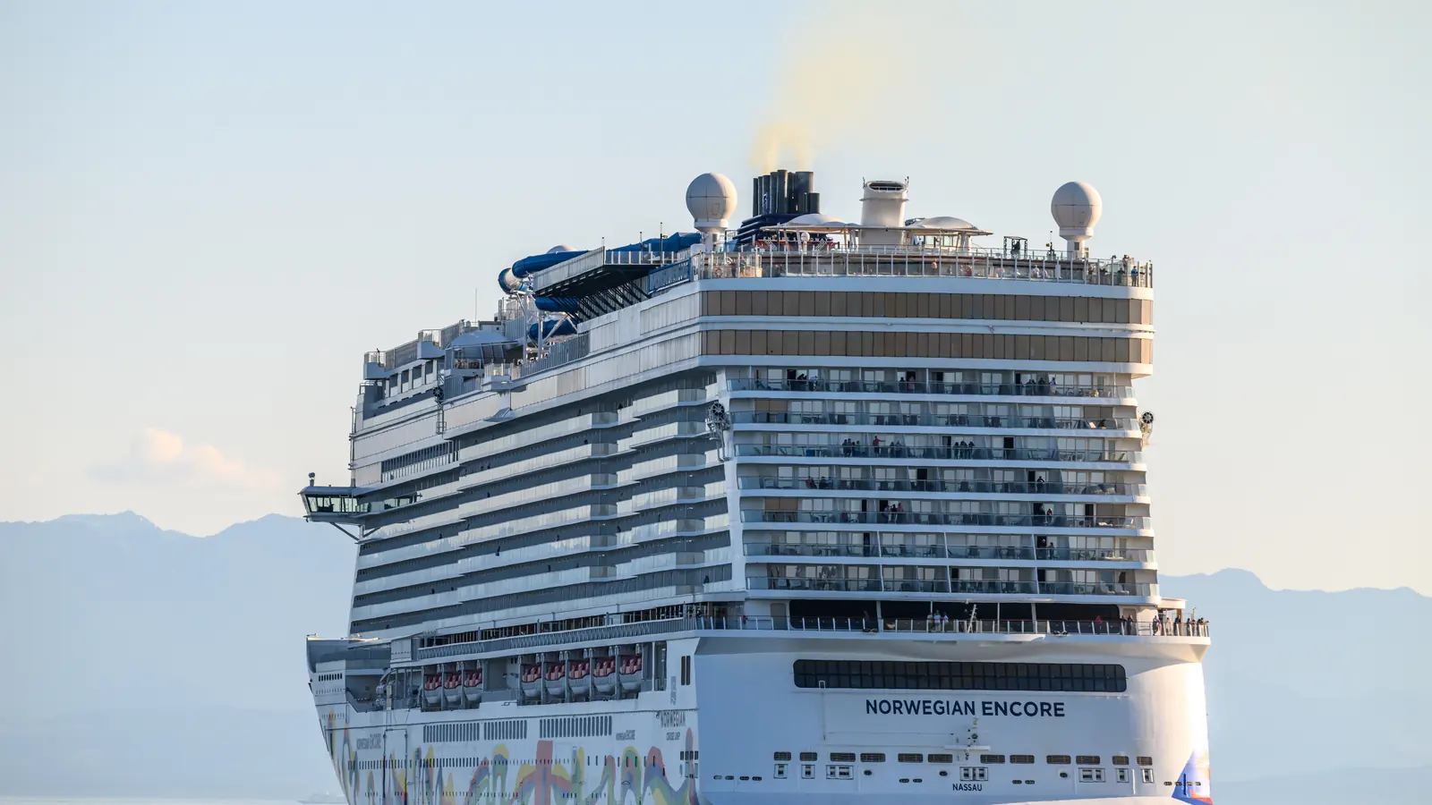 A Norwegian Cruise Line ship alongside at a cruise berth under a bright sky