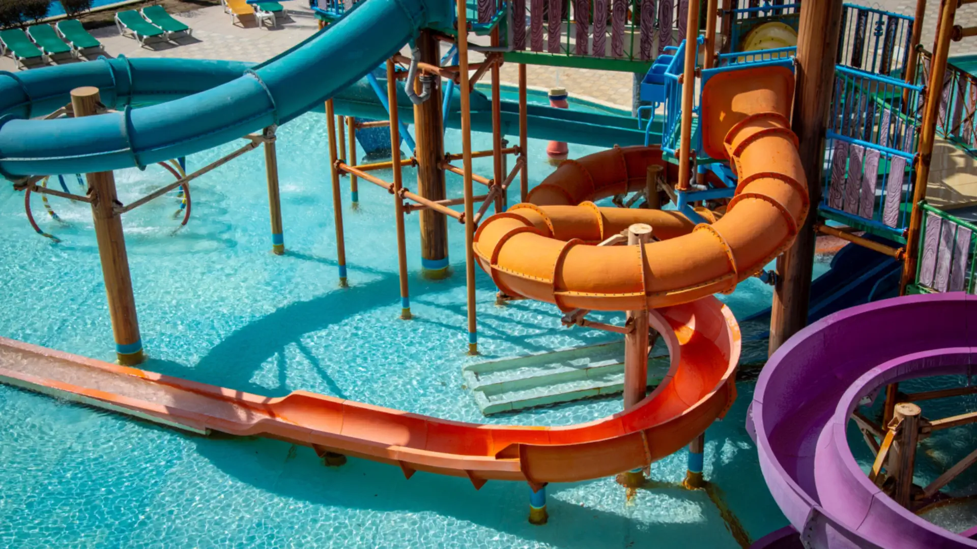 Bright orange, blue and purple water slides twisting over a turquoise pool at a water park