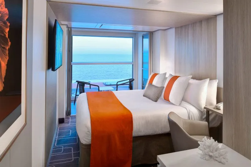 Interior of a Celebrity Edge Single stateroom showing a full-size bed, seating area and the Infinite Veranda floor-to-ceiling window open to the sea