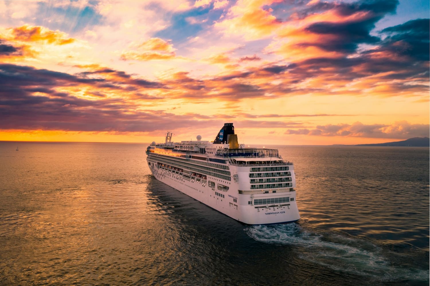 A classic white ocean liner at sea beneath a dramatic golden sunset
