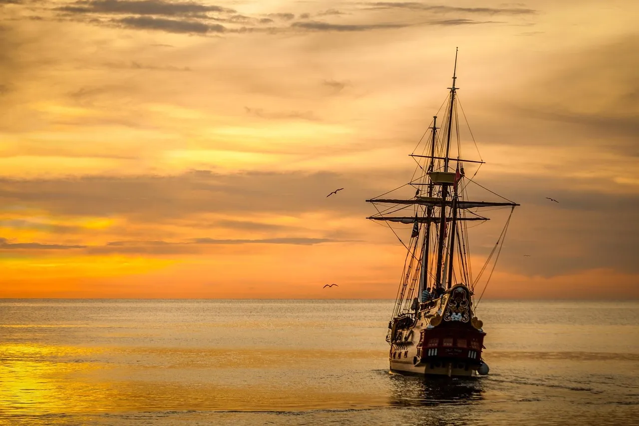 A classic white ocean liner at sea beneath a dramatic golden sunset
