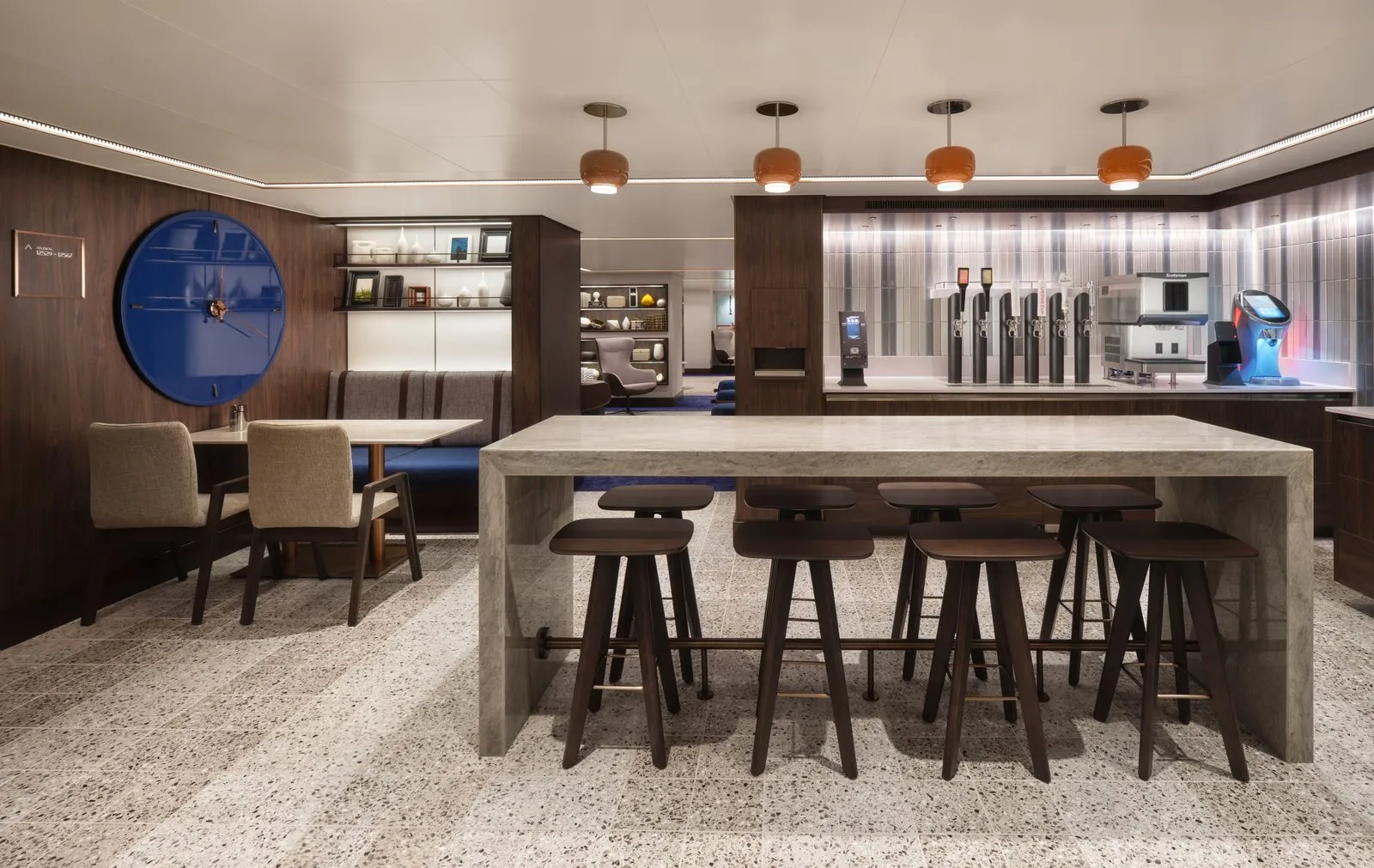 The NCL Prima Studio Lounge interior showing a coffee and espresso bar, concrete island with bar stools, and lounge seating beyond