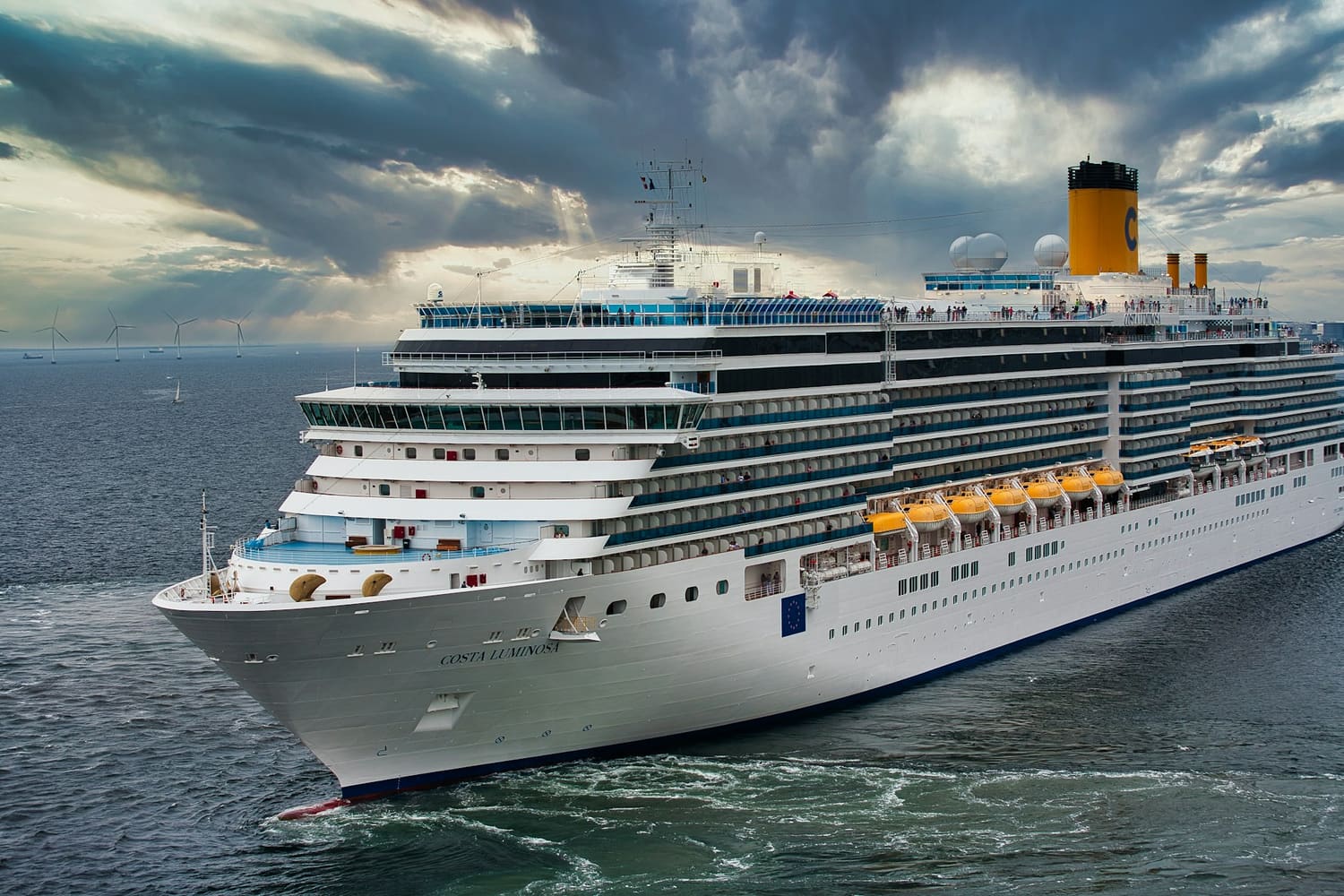 A large modern cruise ship at sea under a dramatic cloudy sky