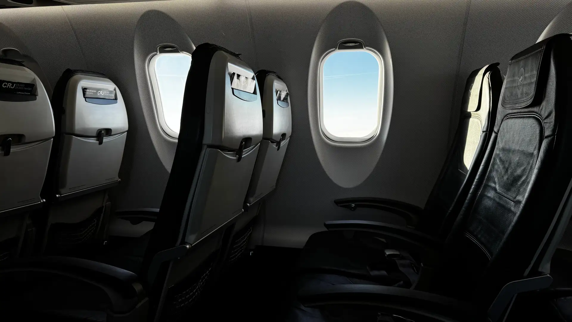 The interior of an empty aircraft cabin with daylight through a window