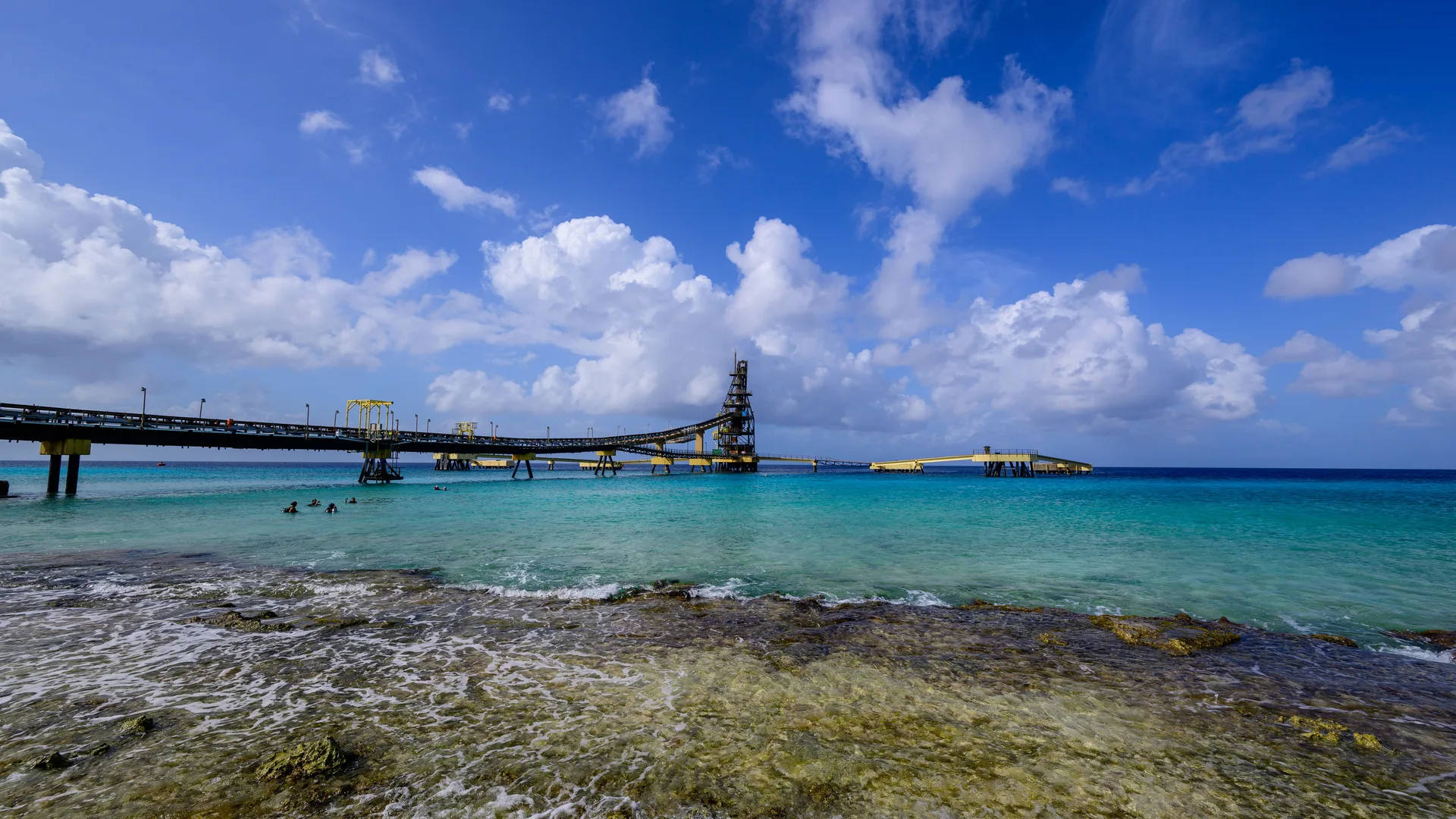 A wooden pier reaching out into clear turquoise Caribbean water