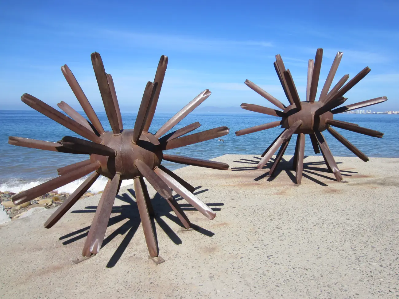 Two large bronze sea-urchin sculptures, 'Erizados', on the Malecón seafront at Puerto Vallarta against a blue sky