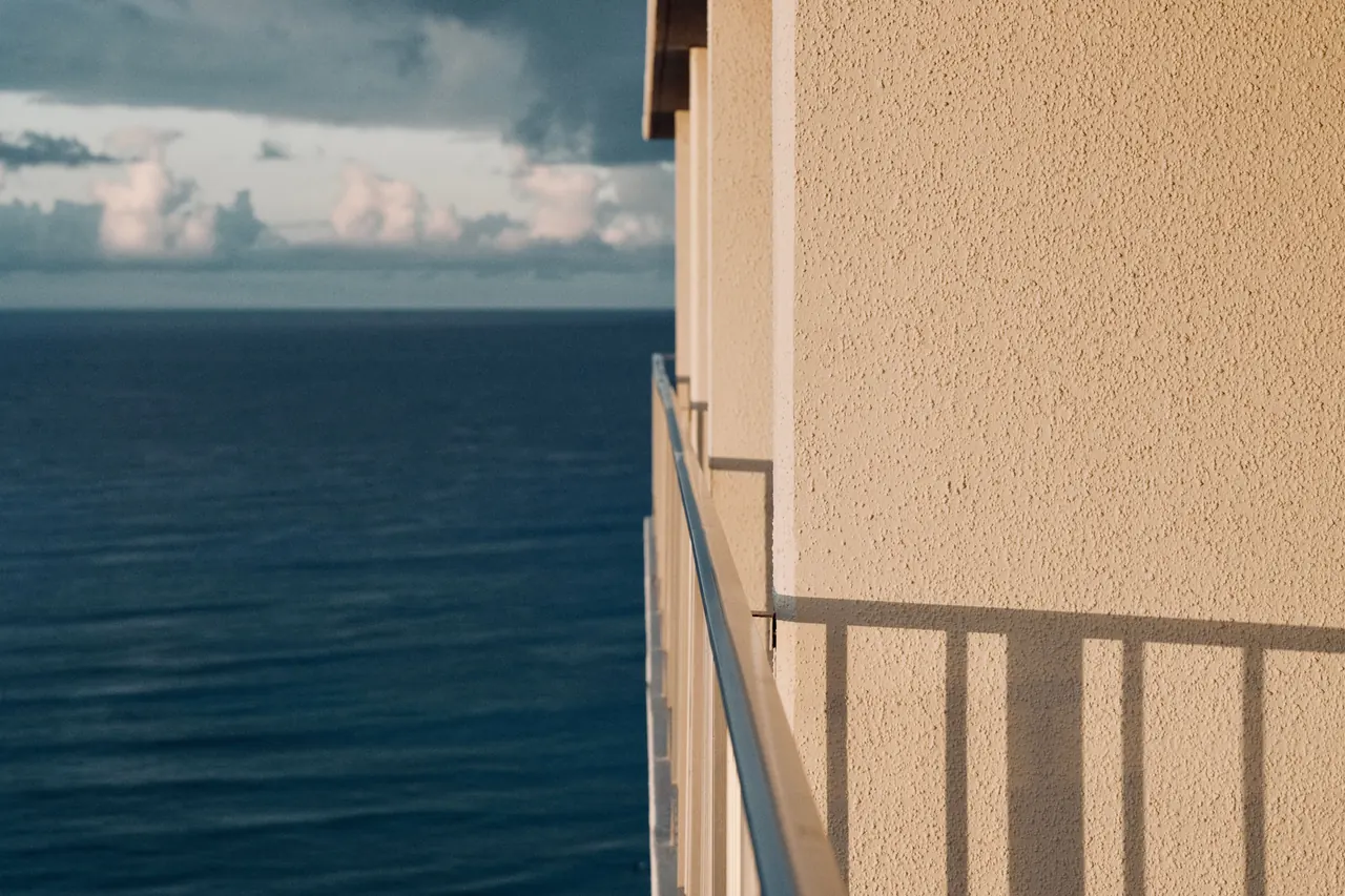 Calm ocean view from a balcony in Honolulu, Hawaii, showing a clear sky and building facade.