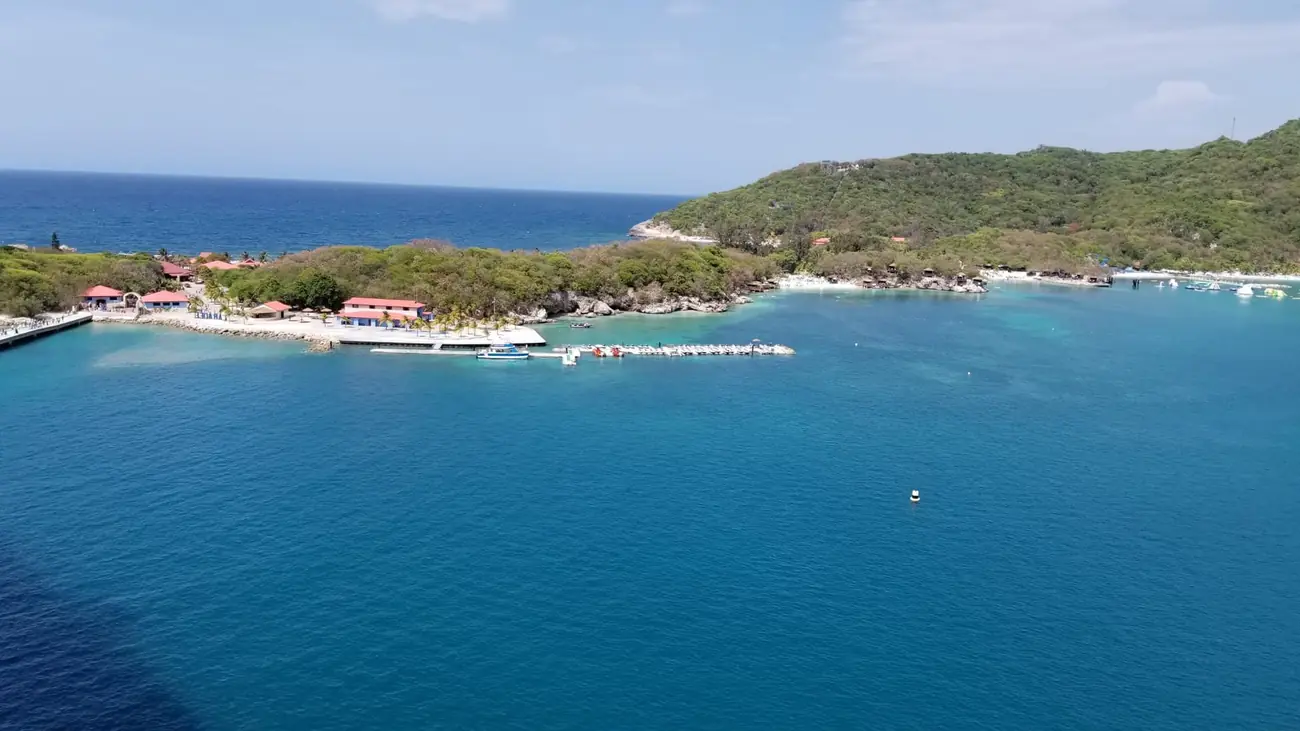A beach at Labadee with loungers along the sand and forested hills rising behind