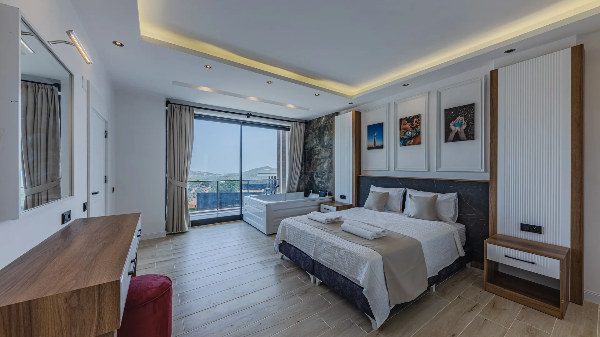 A modern hotel suite with a large bed and a balcony beyond