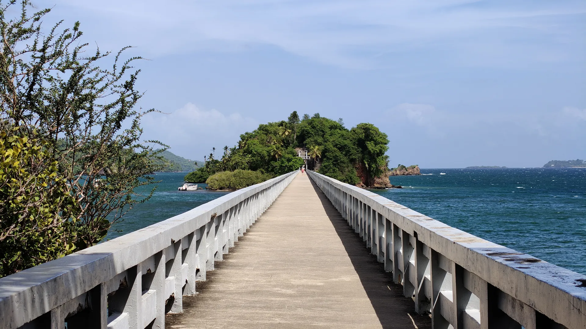 A long white footbridge over blue water leading to a small wooded cay off Santa Bárbara de Samaná, Dominican Republic