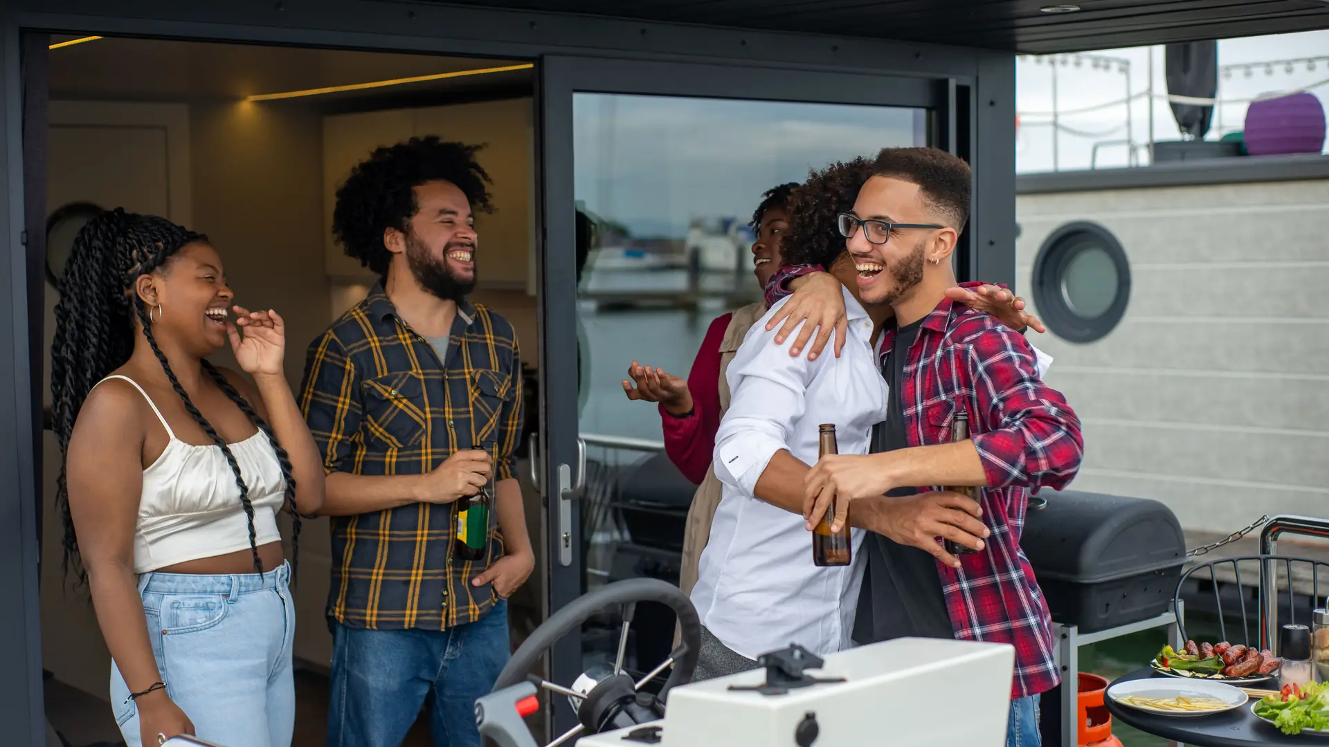 A small group of friends laughing and hugging as they greet each other on the deck of a boat