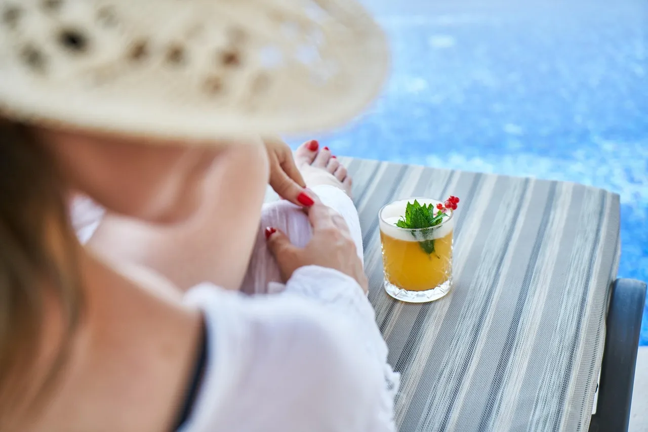A solo traveler on a balcony overlooking a calm, blue ocean