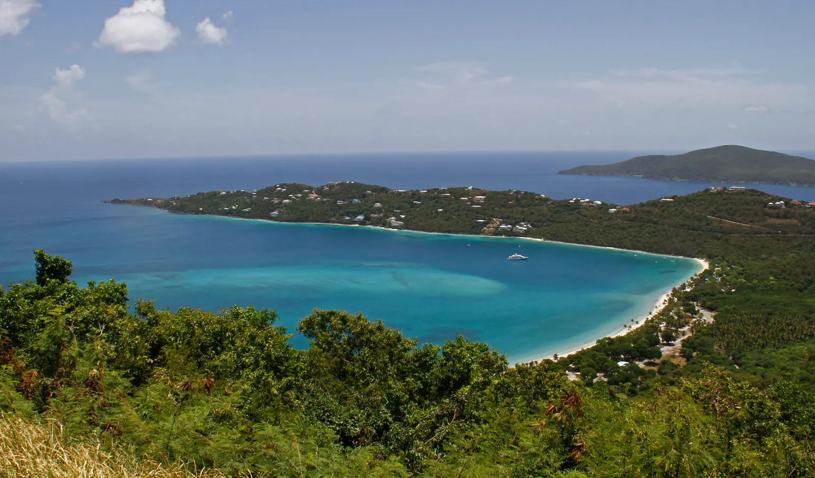 Magens Bay on St. Thomas seen from the hillside above, a long curve of pale sand enclosing calm turquoise water