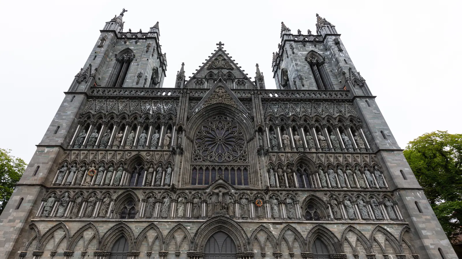 The west front of Nidaros Cathedral in Trondheim, its carved stone facade rising above the churchyard