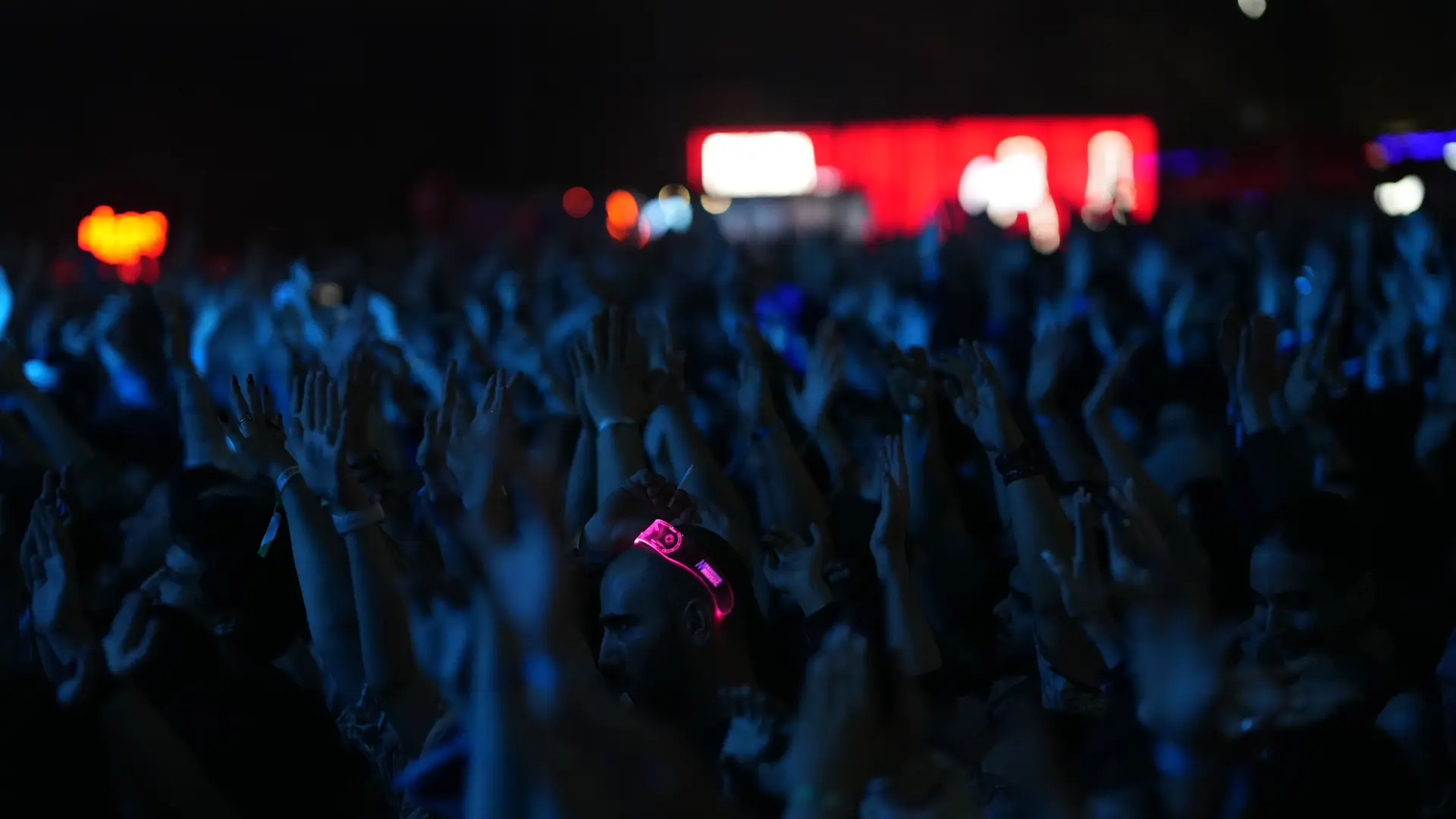 A crowd of people dancing under stage lights at a night-time party