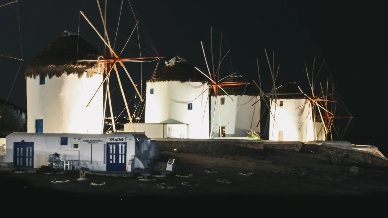 The windmills of Mykonos lit against a deep blue night sky