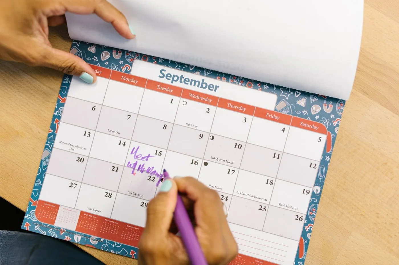 A hand marking a date on a September desk calendar