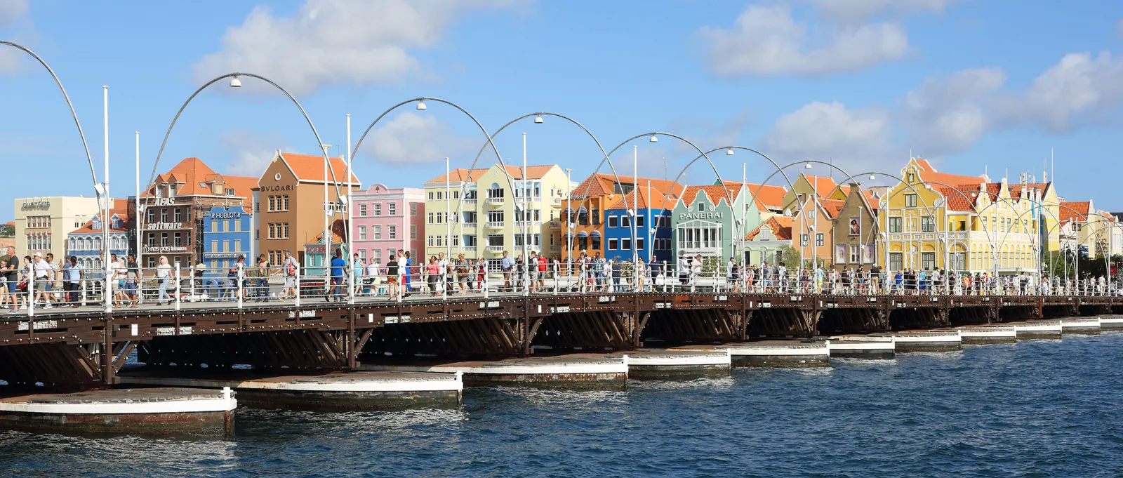 The colourful Dutch colonial facades of the Handelskade waterfront in Willemstad, with the Queen Emma pontoon bridge across St. Anna Bay