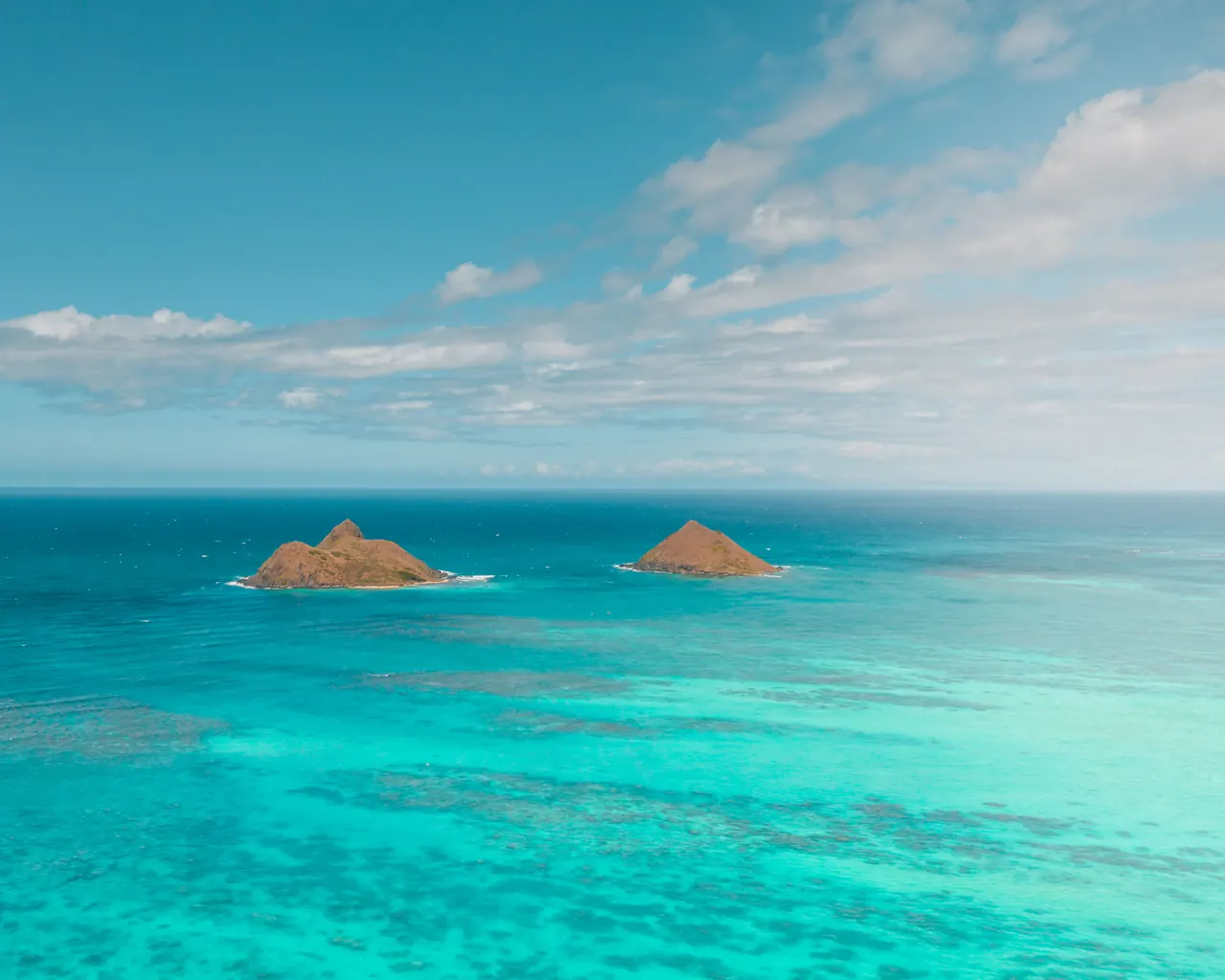 Beautiful aerial shot of Mokolua Islands surrounded by turquoise ocean and blue sky.