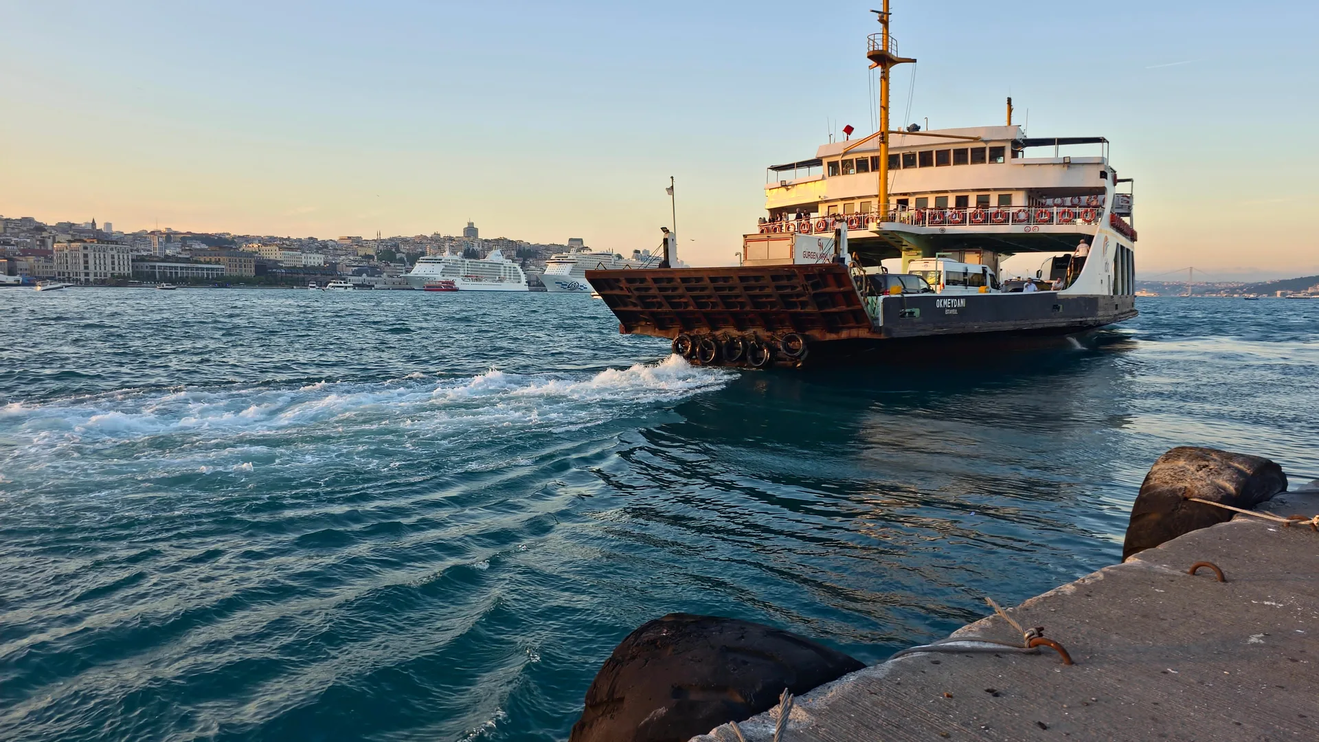 A ship departing a waterfront at sunset