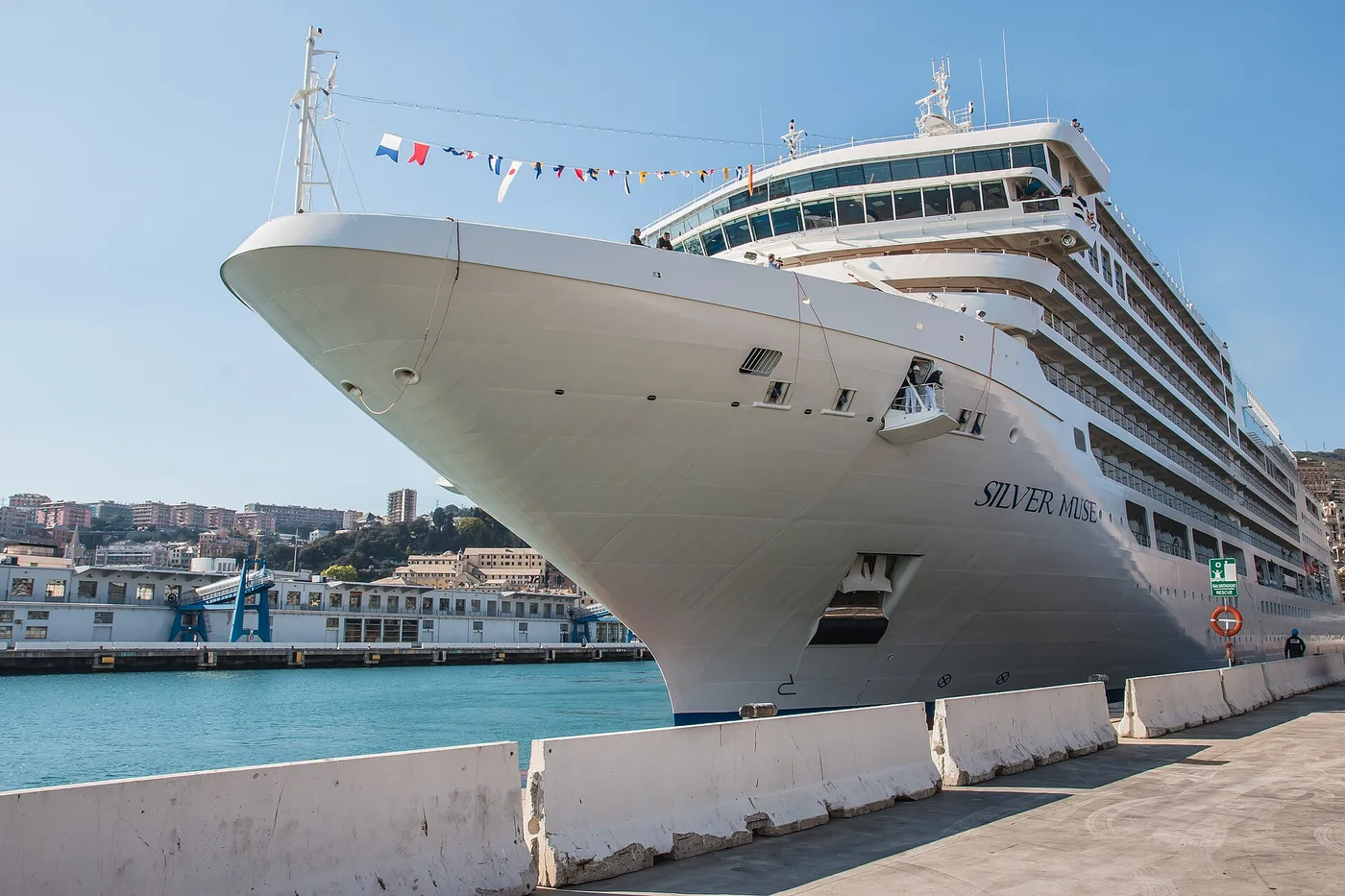 Silversea's Silver Muse alongside at Genoa, bow angled toward the camera under a clear sky
